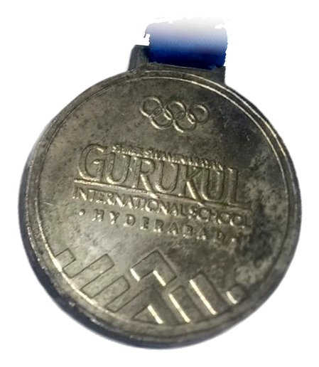 The Gurukul Olympics 2023 medal, engraved Gurukul International School Hyderabad, on its blue ribbon